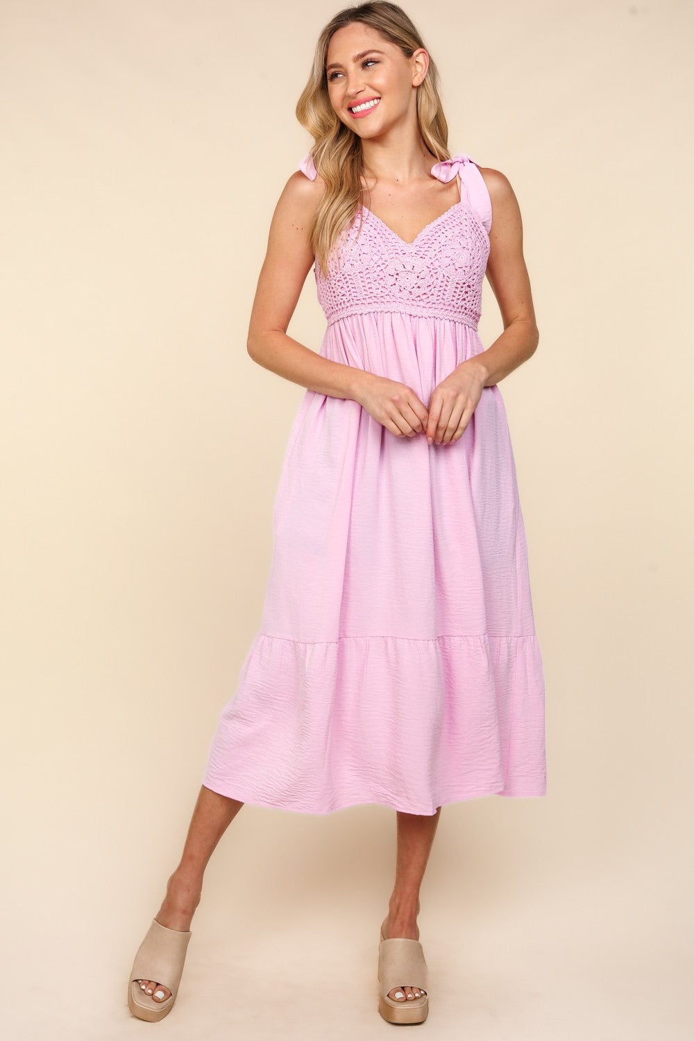 A woman in the Haptics Crochet Lace Ruffle Hem Cami Midi Dress poses against a beige background. She wears neutral-colored platform sandals.