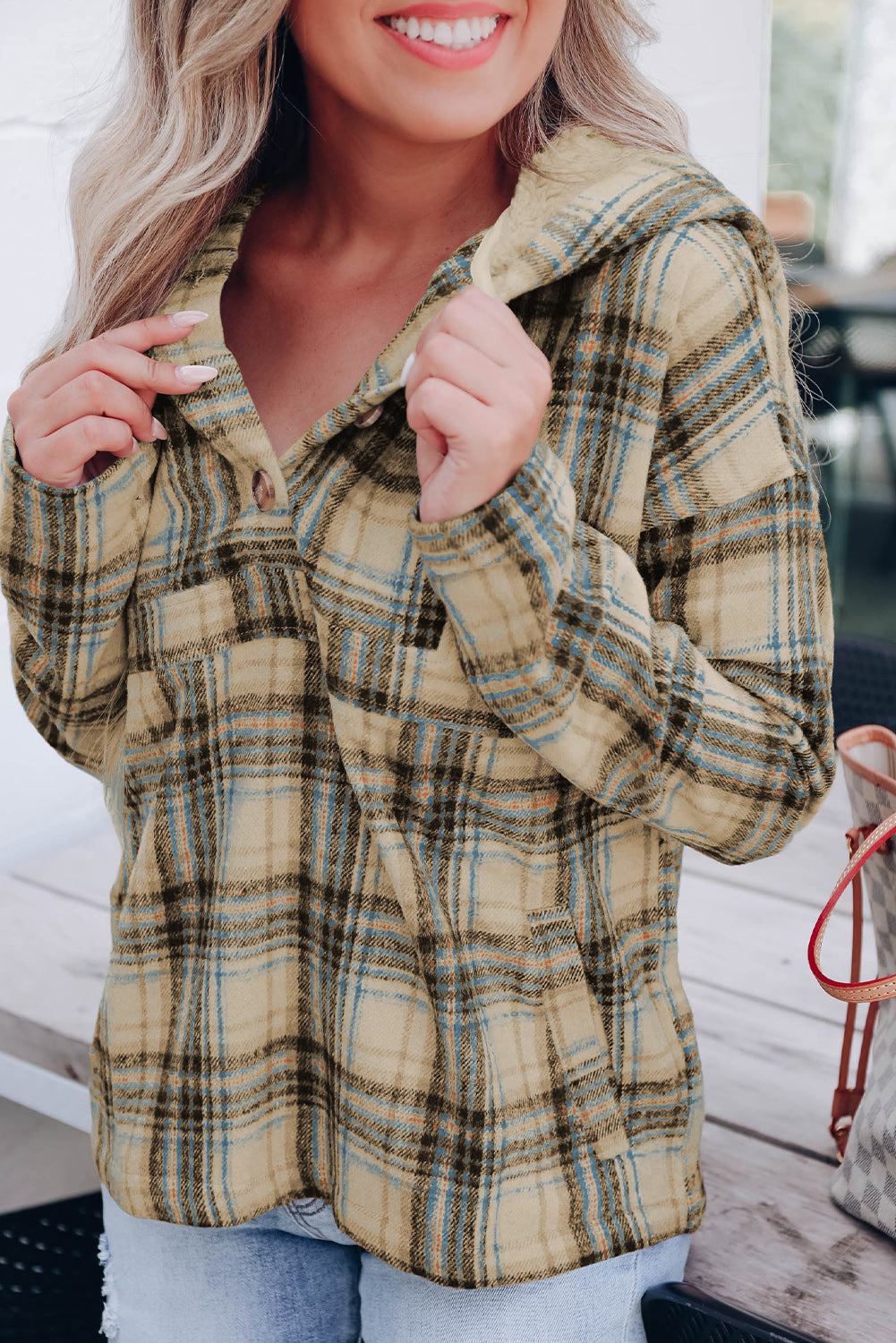 A person with long blonde hair, seen from the back, wearing a Khaki Plaid Button Neck Pocketed Pullover Hoodie and denim shorts, stands on a porch.