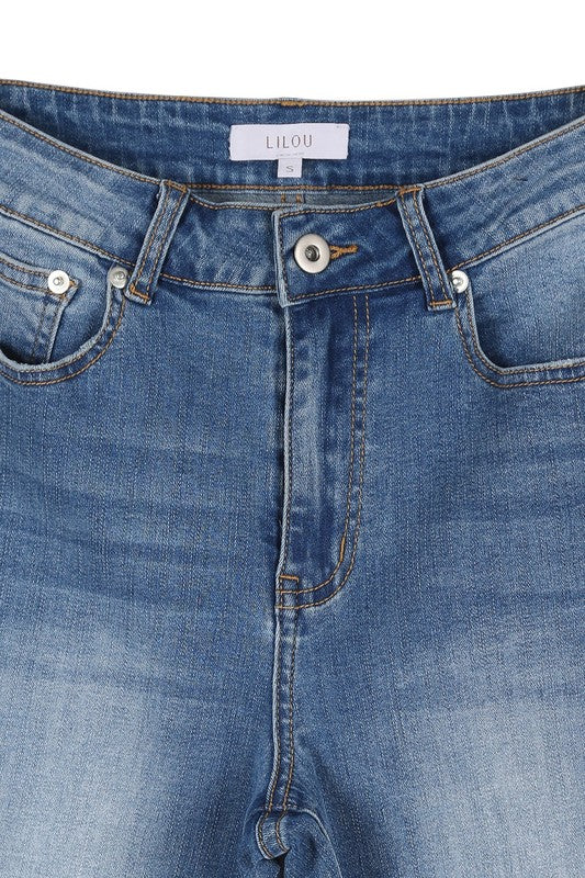 Someone wearing a sleeveless top and Dark Wash Distressed Skinny Jeans is kneeling on a white chair against a beige background.