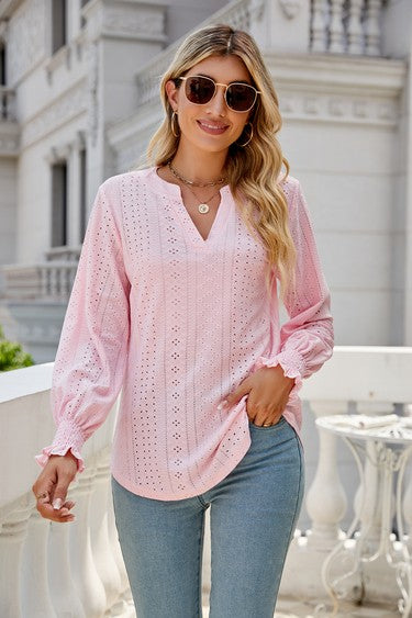 A woman wearing sunglasses, a light pink Women Long Sleeve TOP, and blue jeans stands on a balcony.