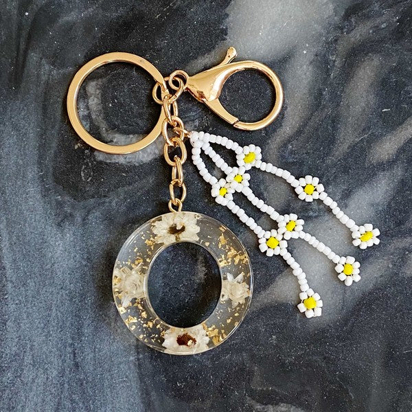 Baby Daisy Initial Key Chain alphabet keychains with real daisy flowers and gold flakes on a marble surface.