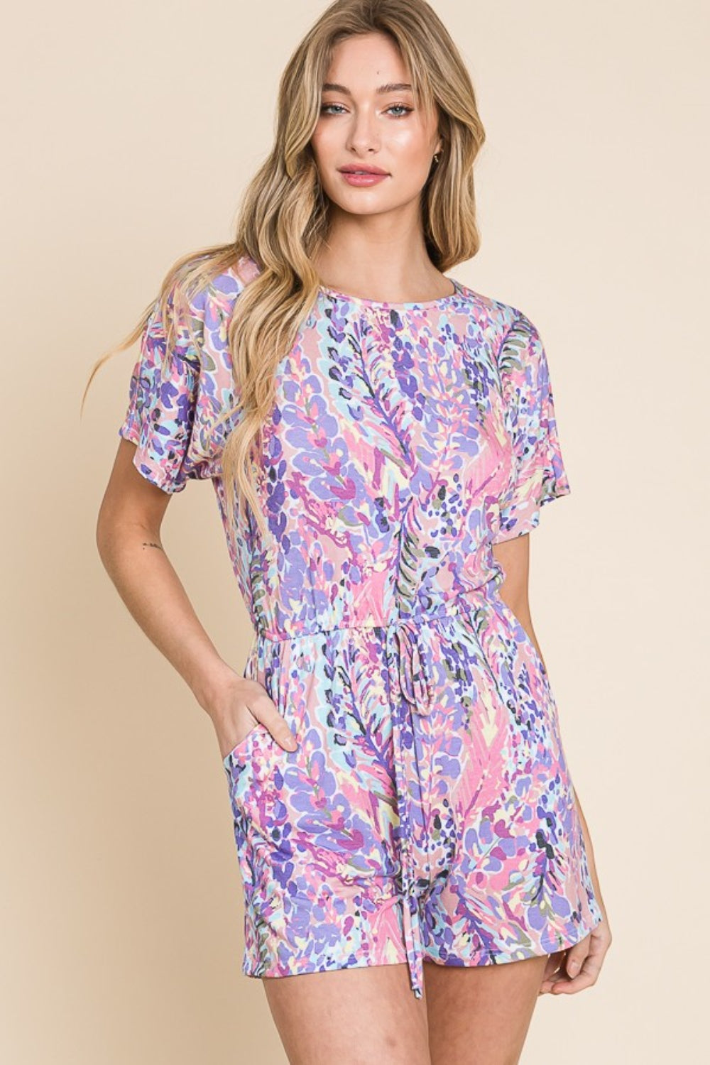 A person wearing the BOMBOM Print Short Sleeve Romper with Pockets stands against a plain background, making it a perfect addition to any summer wardrobe.