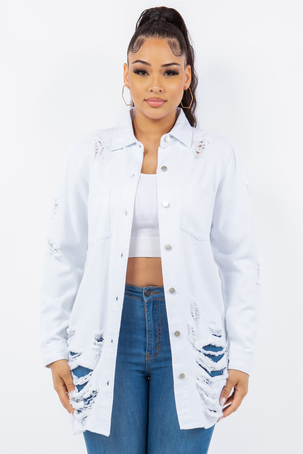 A woman wearing an American Bazi Distressed Button Up Long Sleeve Denim Jacket over a white crop top and blue jeans stands facing the camera against a plain background.