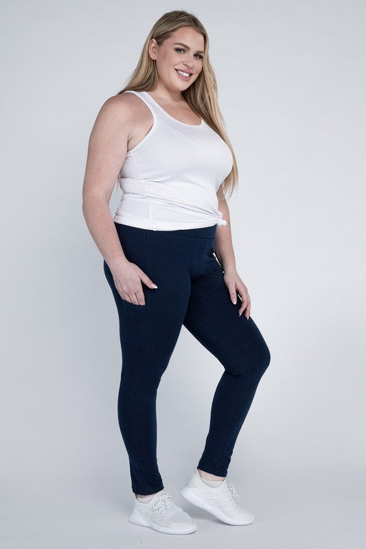 A person with long hair in casual attire is wearing a white t-shirt, Plus Everyday Leggings with Pockets in black, and white sneakers. They are holding a white cap and sporting a black crossbody bag.