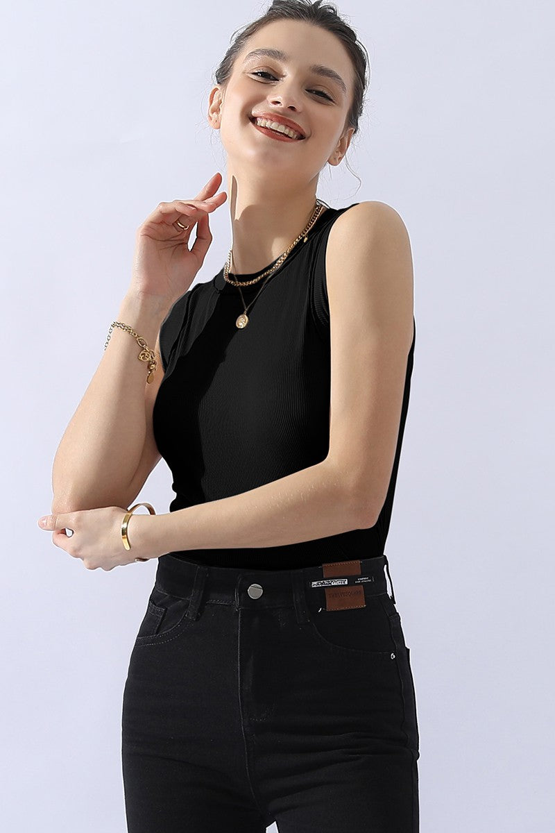 A person wears a versatile and comfortable Ninexis Ribbed Round Neck Tank in black, paired with black jeans and gold jewelry, smiling against a white background.