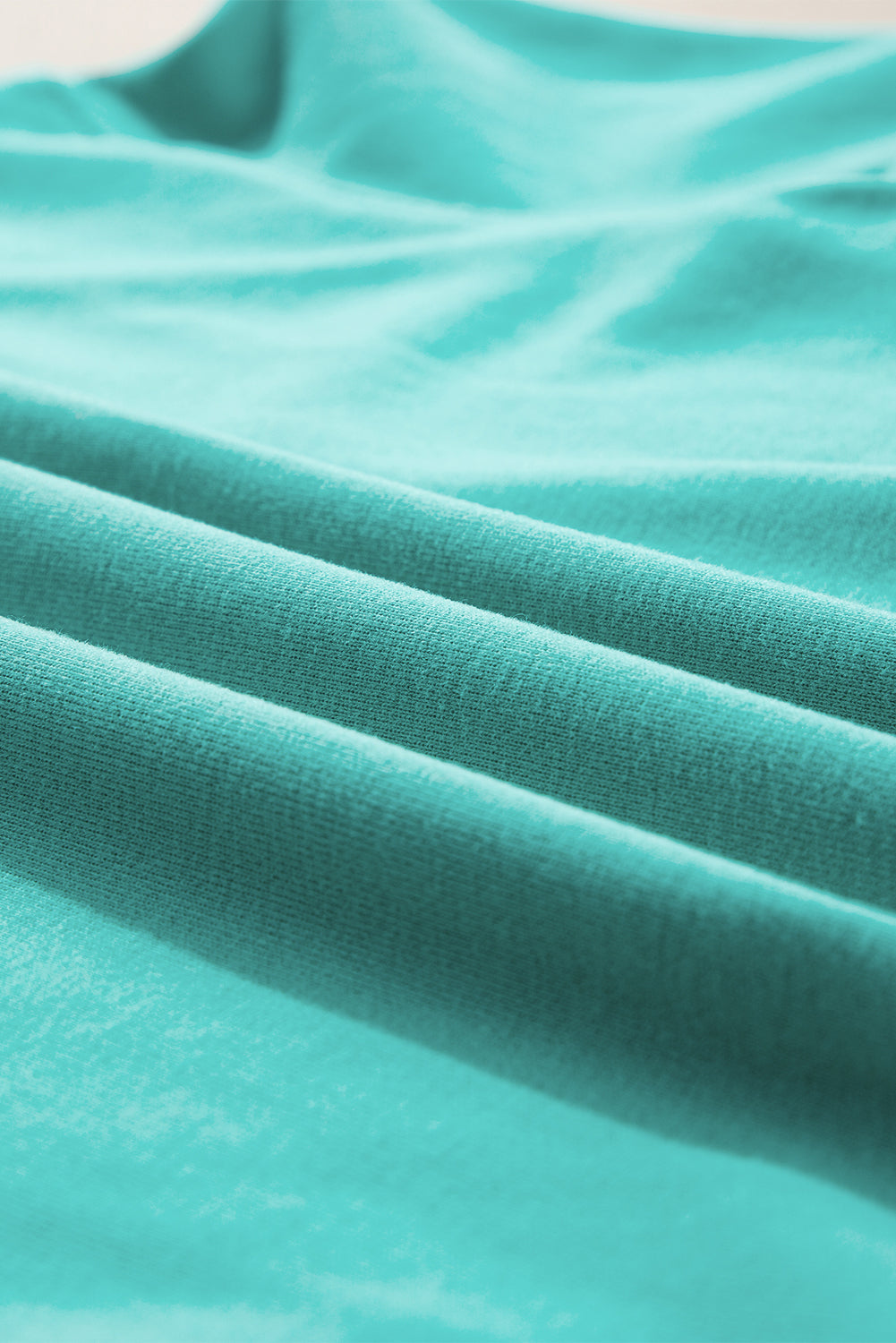 Person with long hair wearing an Aruba Blue Plain Drop Shoulder Crewneck Pullover Sweatshirt and carrying a floral crossbody bag, seen from the back, walking outdoors.