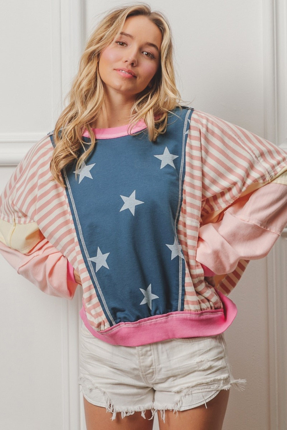 A woman wearing a BiBi Stars and Stripes Round Neck Long Sleeve Top paired with white shorts, standing against a plain background.