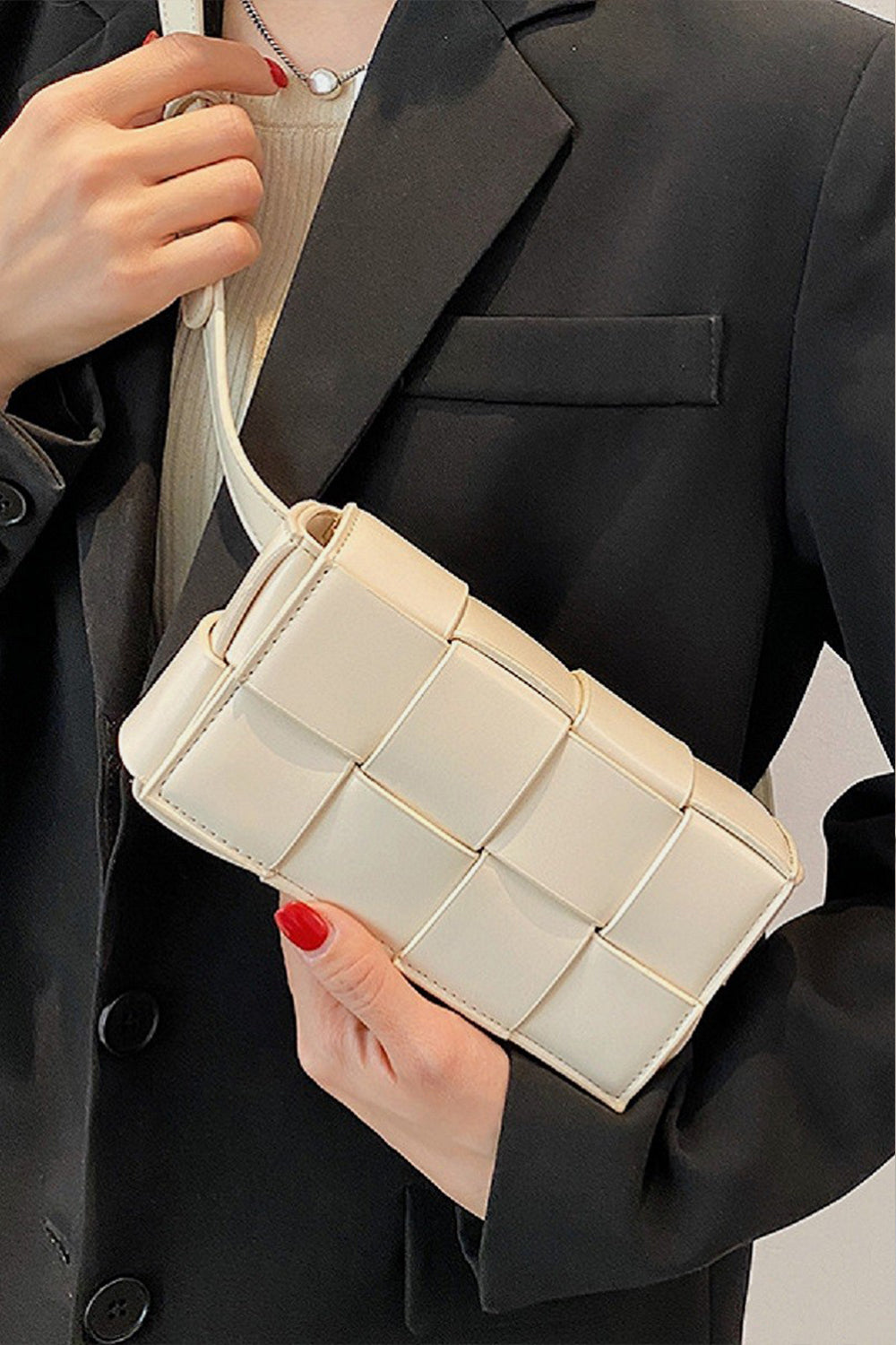 Person wearing a white button-up shirt and holding a black Zenana Vegan Leather Woven Crossbody Bag.