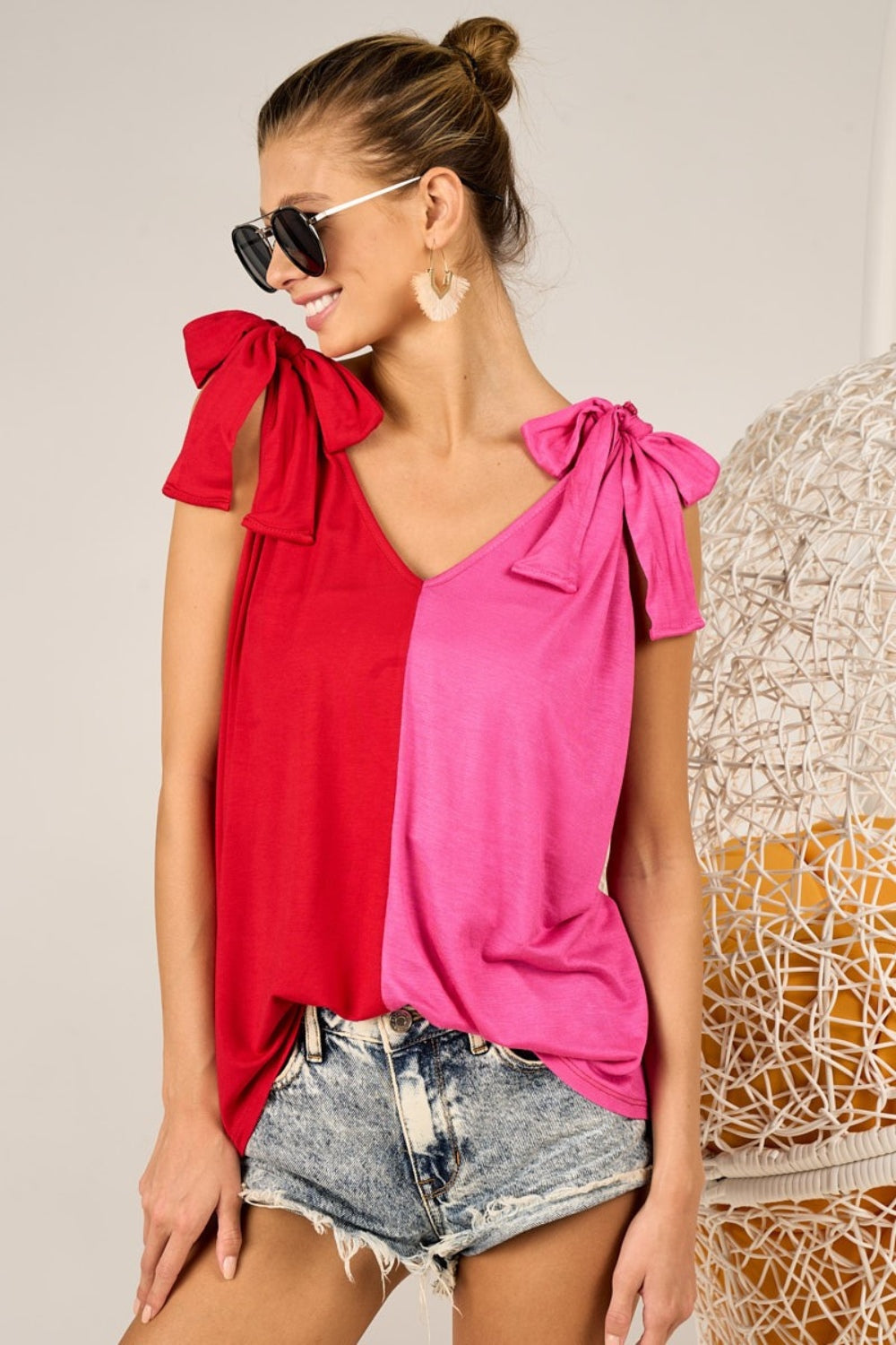 A person wearing the stylish BiBi Shoulder Ribbon Tied Contrast Tank, paired with denim shorts, sunglasses, and earrings, poses against a neutral background.