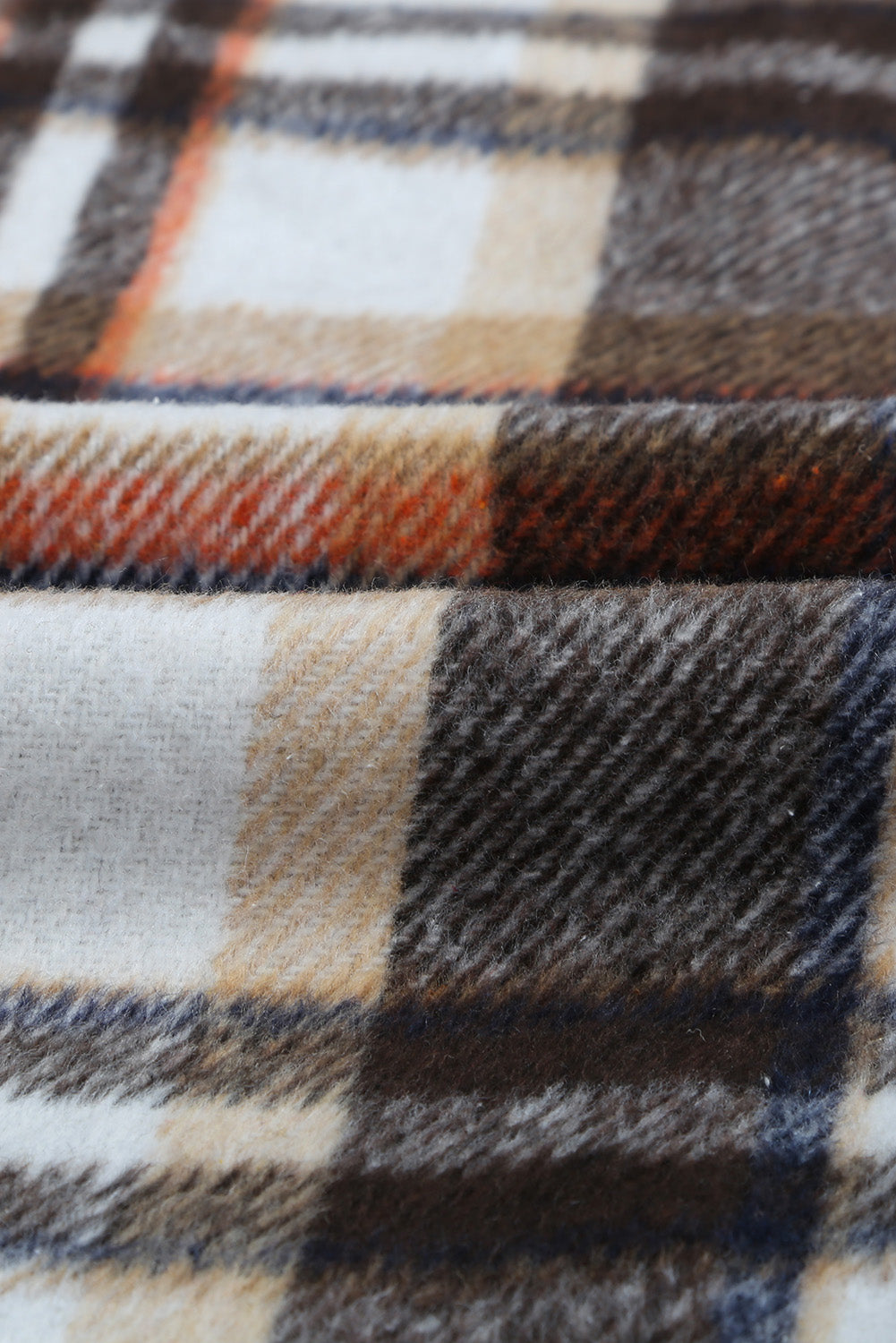 A person wearing a Brown Plaid Button Up Long Sleeve Flannel Shacket layered over a white top with ripped jeans and holding a brown handbag stands against a textured gray wall.