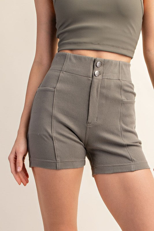 A person wearing a green ribbed crop top and high-waisted gray Cotton Stretch Twill Short Pant with button closure. The slim-fit short boasts a high-rise design, making the outfit both casual and fitted.