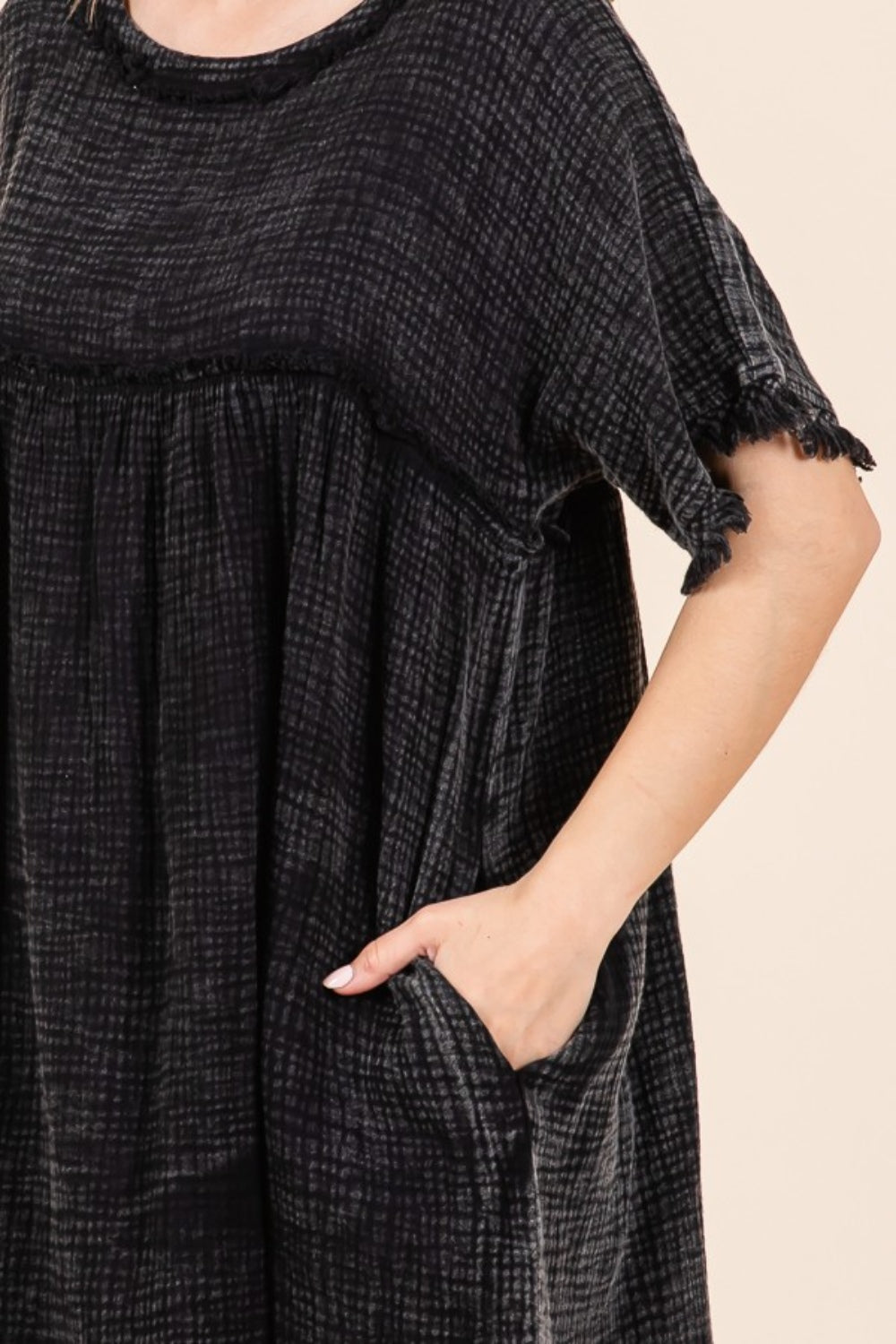 A person is wearing the Culture Code Full Size Short Sleeve Babydoll Texture Dress with Pockets, in black, standing against a plain background.