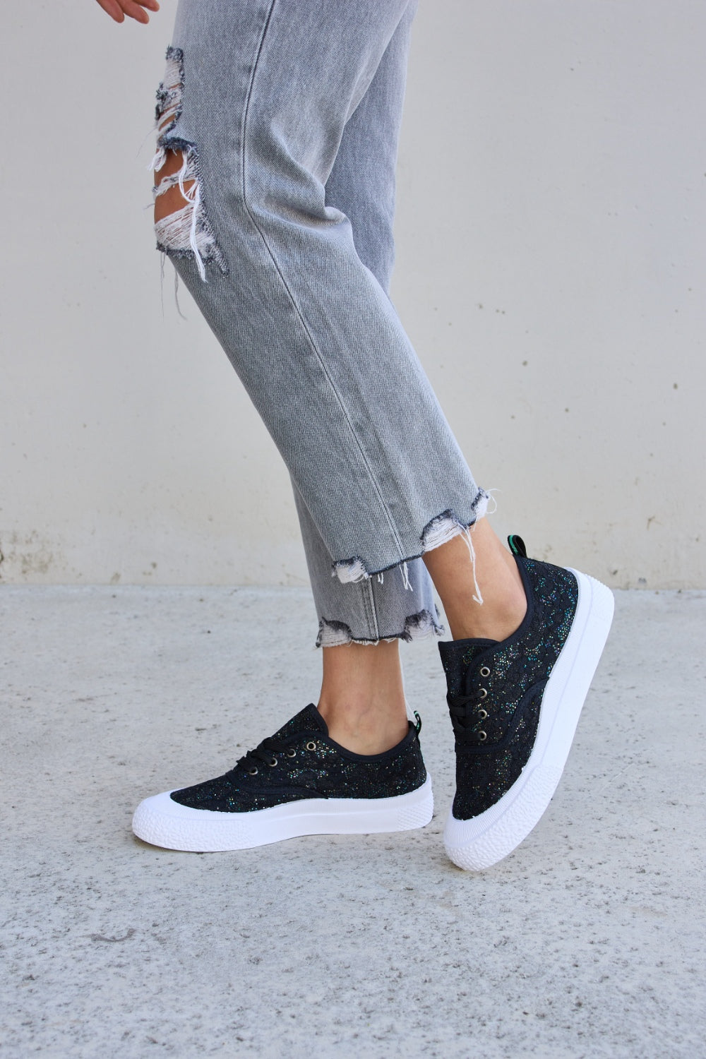 Person wearing ripped gray jeans and Forever Link Sequin Lace-Up Platform Sneakers.