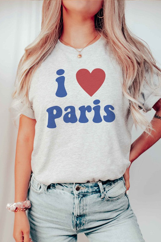 Person wearing a unisex "I LOVE PARIS" graphic tee made from 100% Airlume combed and ringspun cotton, high-waisted denim shorts, and a yellow knit sweater draped over their arms.