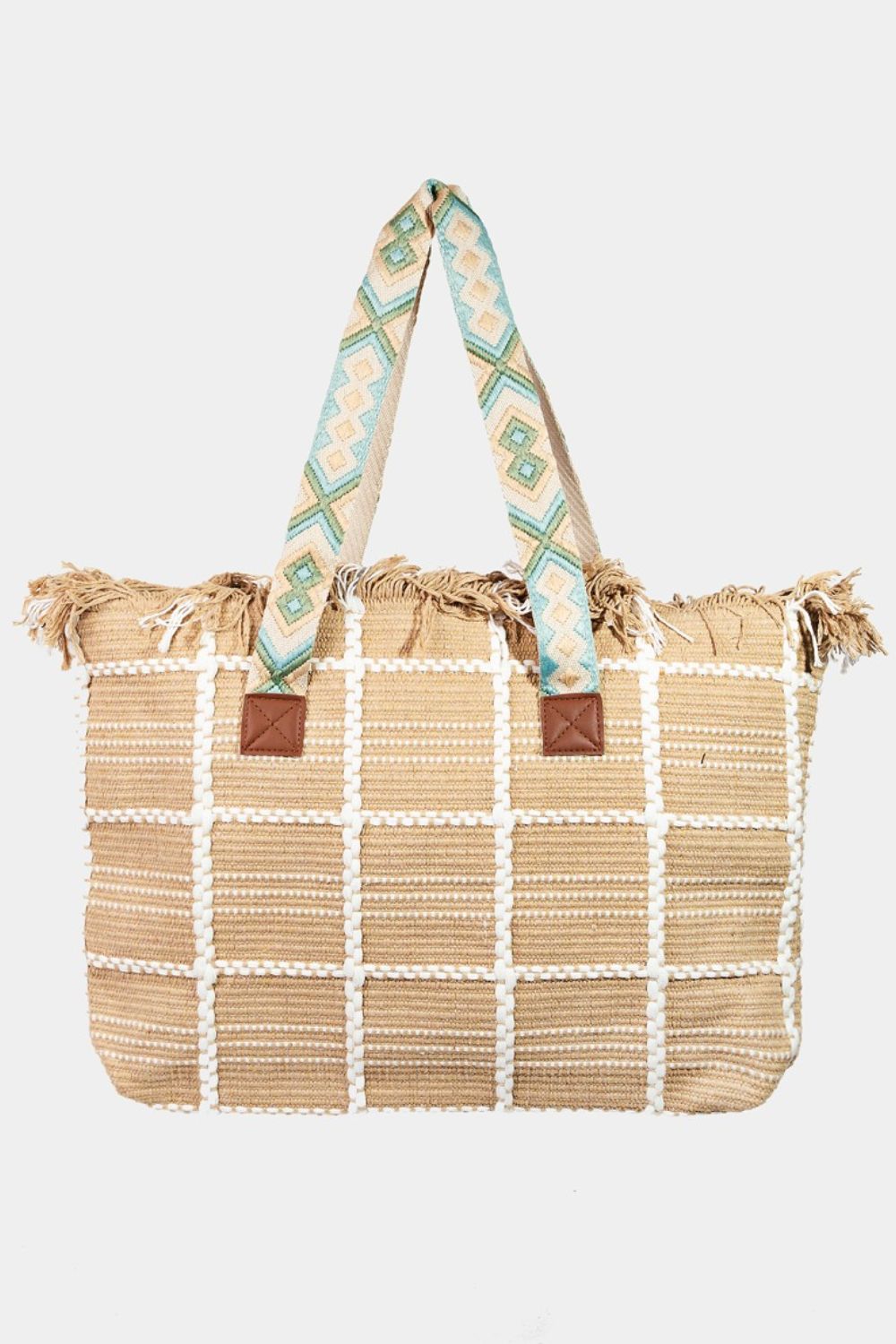 A woman in casual attire of a white t-shirt and jeans models the Fame Fringe Detail Checkered Tote Bag by her side, highlighting its distinctive fringe accents and chic checkered design. She poses near a potted plant and a white decorative vase, accentuating the tote's elegant appeal.