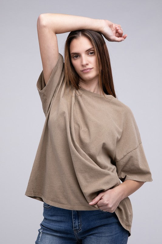 A person with long hair wearing an Oversized T-Shirt in beige with short sleeves and blue jeans, standing against a neutral background.