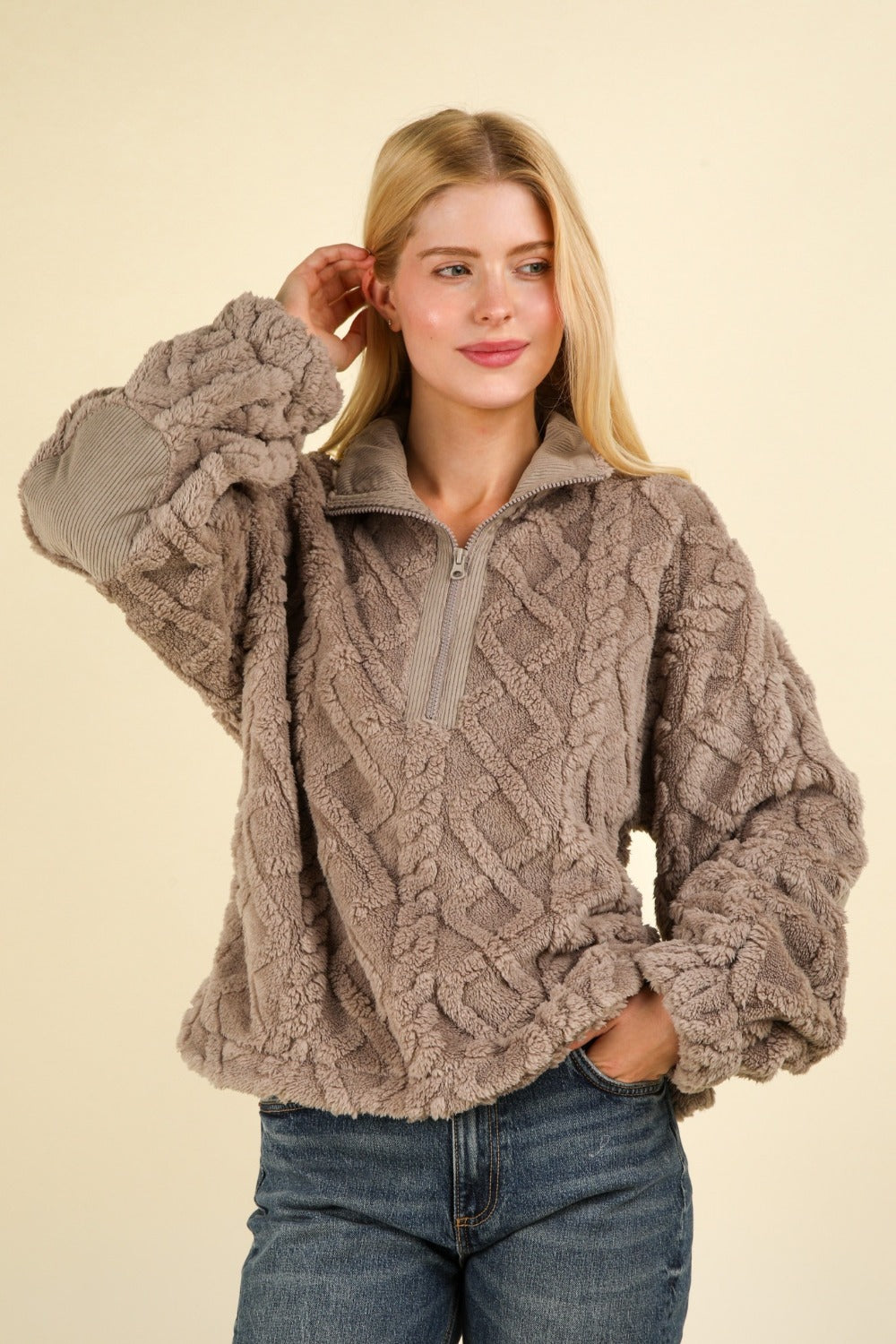 A person smiling and wearing the VERY J Fuzzy Fleece Half Zip Cable Pattern Sweatshirt in gray, along with blue jeans.