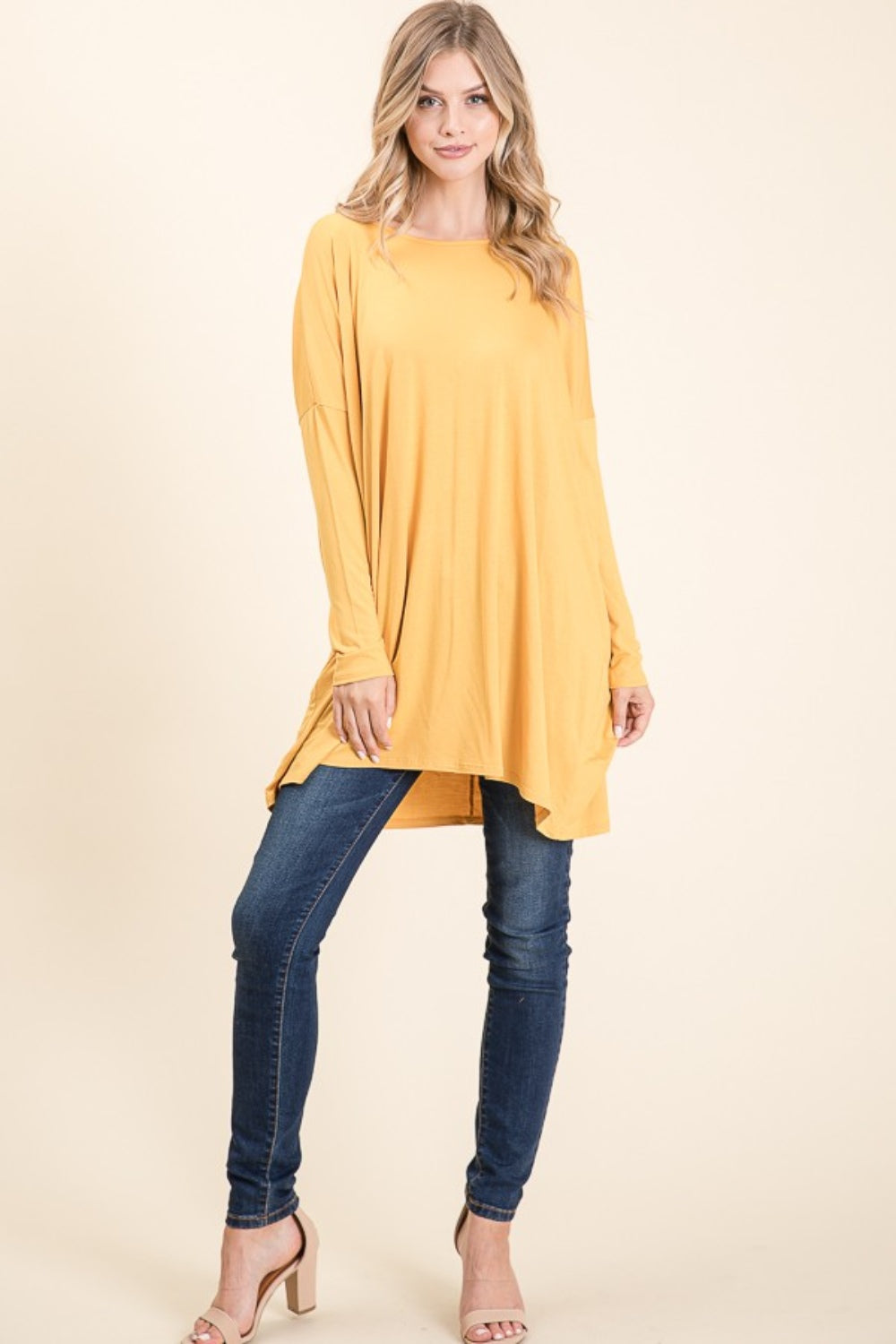 A woman with long blonde hair is wearing a versatile and comfortable, loose-fitting BOMBOM Round Neck Long Sleeve Oversized Top in yellow and blue jeans. She is smiling and standing against a plain light background.