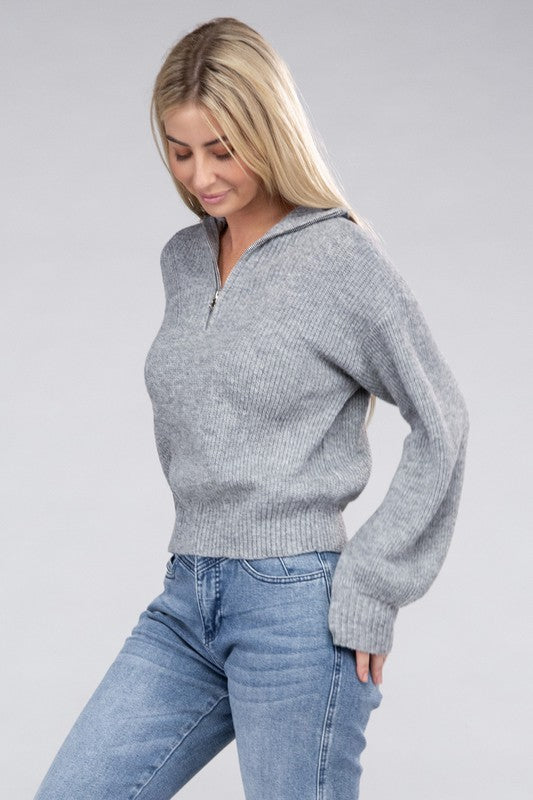 A person with long blonde hair wears a stylish cozy top—an Easy-Wear Half-Zip Pullover in grey—and blue jeans while looking down.