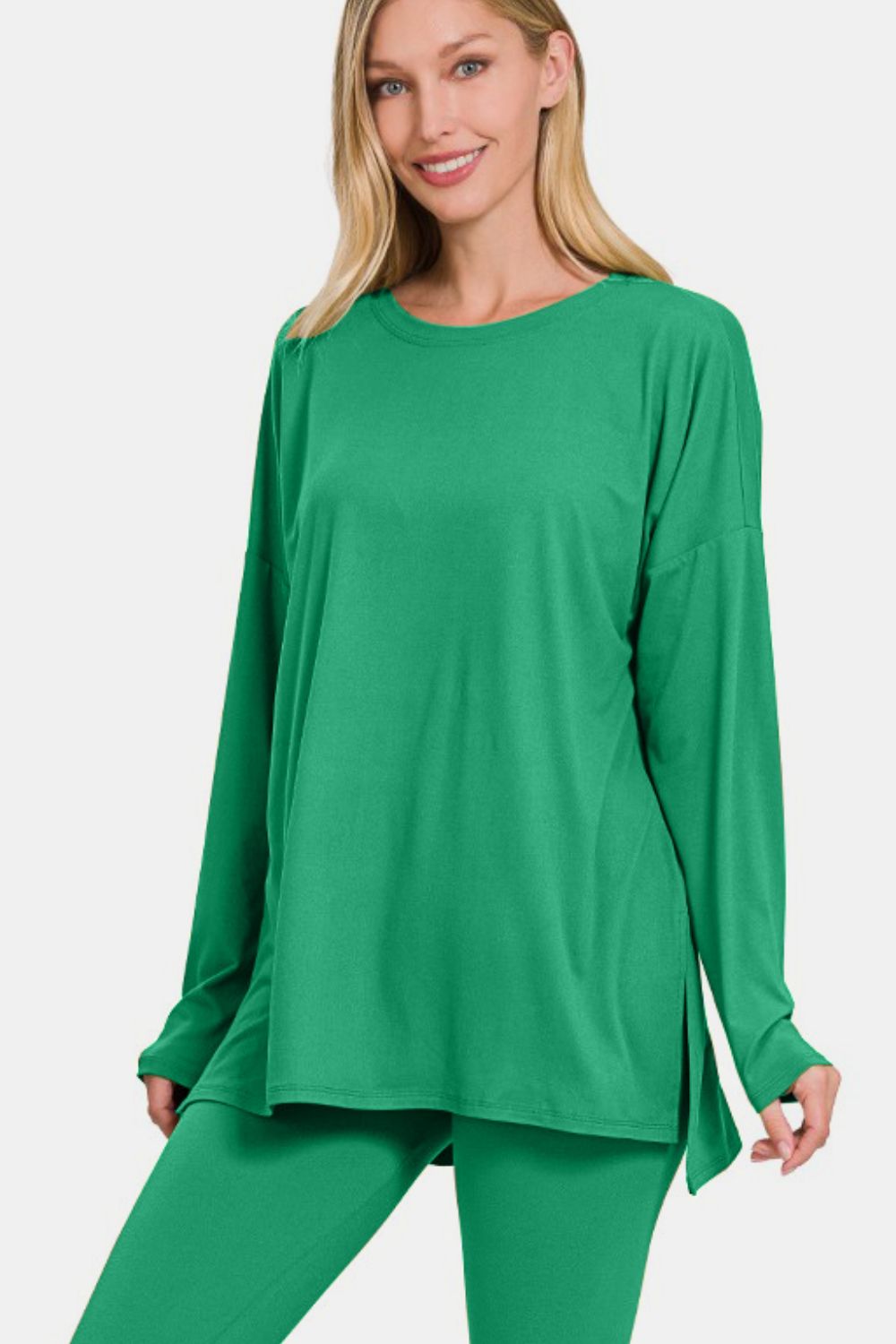 A person wearing the Zenana Full Size Brushed Microfiber Top and Leggings Lounge Set in bright green stands with one hand on their hip.