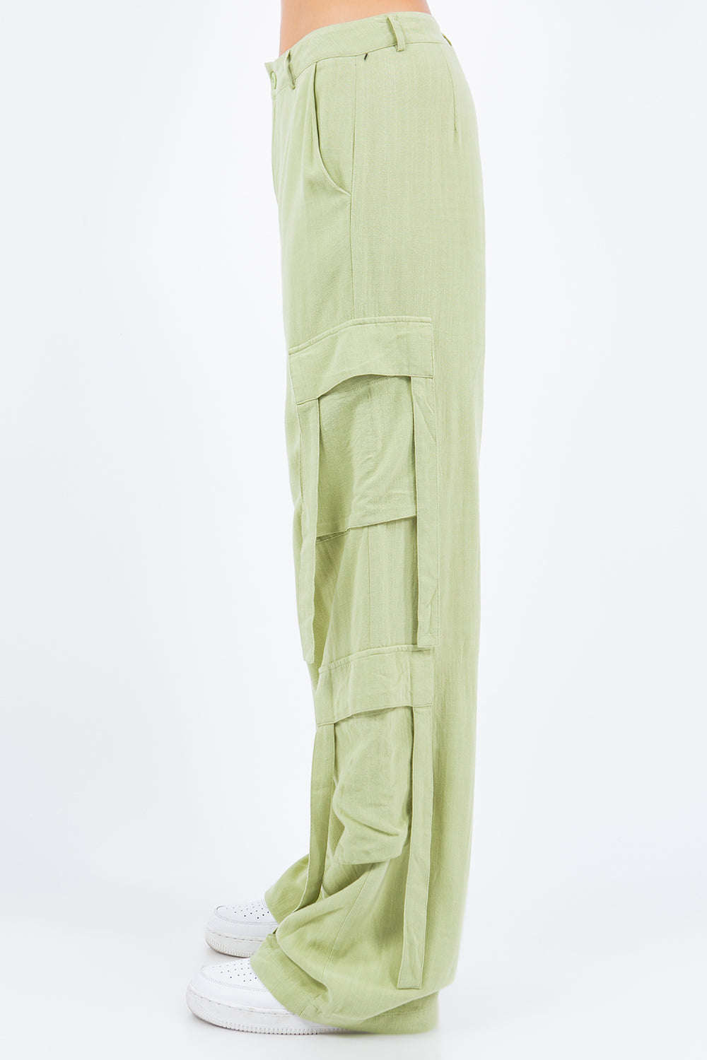 A person is wearing American Bazi light green linen wide leg cargo pants with multiple pockets and white sneakers.