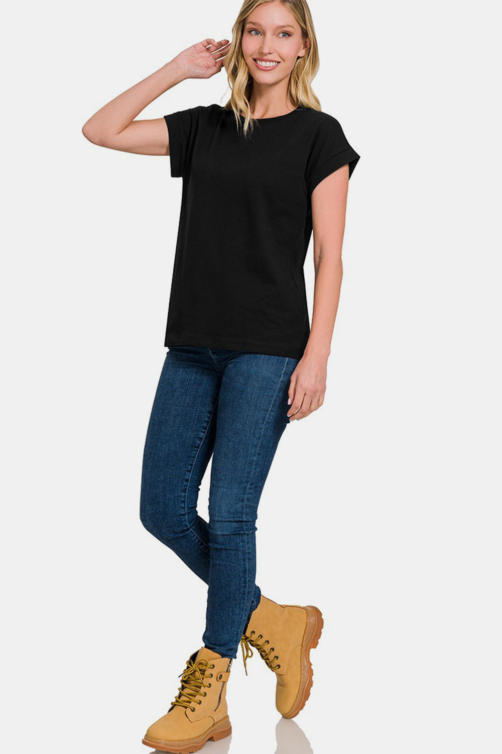 A woman with blonde hair is wearing a plain black Zenana Crew Neck Short Sleeve T-Shirt made of 100% cotton and blue jeans, standing against a white background.