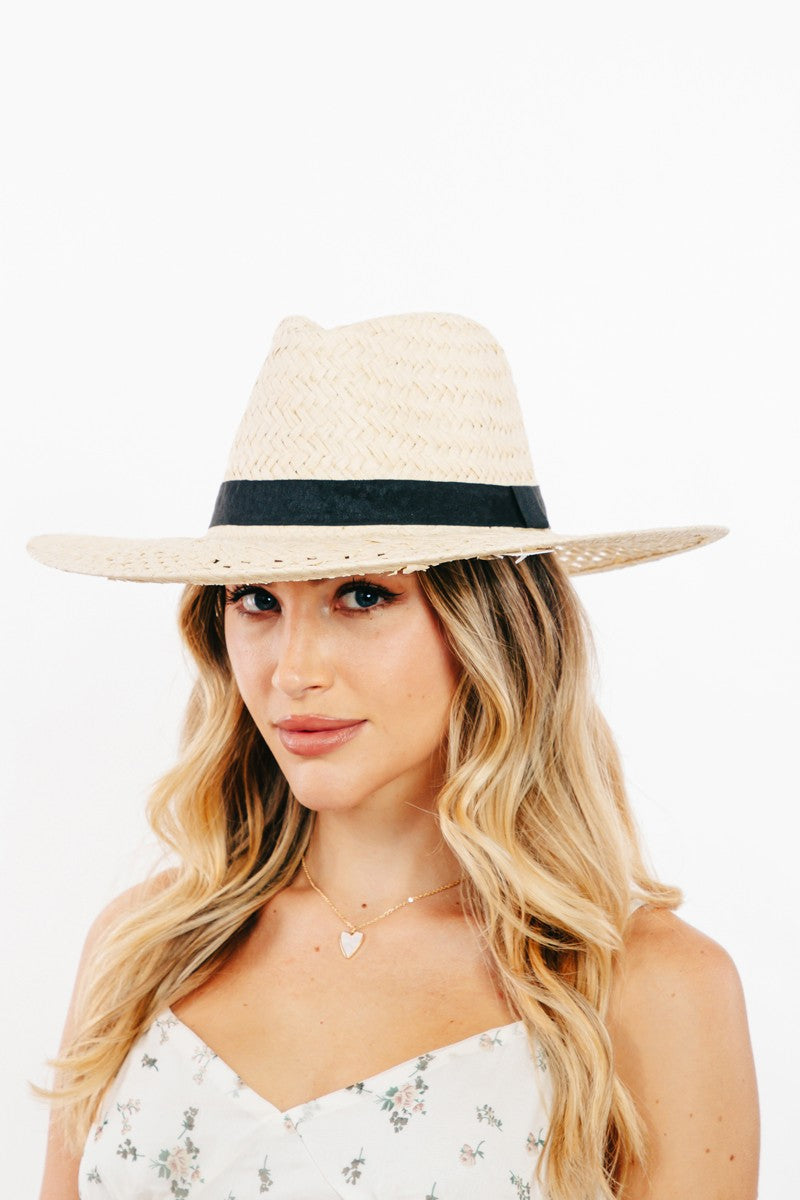 The Fame Basket Weave Straw Sun Hat, featuring a black band and ideal as a fashion accessory, is showcased on a clear stand against a white background.