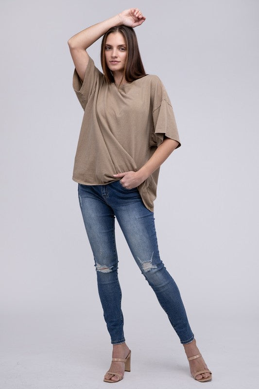 A person with long hair wearing an Oversized T-Shirt in beige with short sleeves and blue jeans, standing against a neutral background.