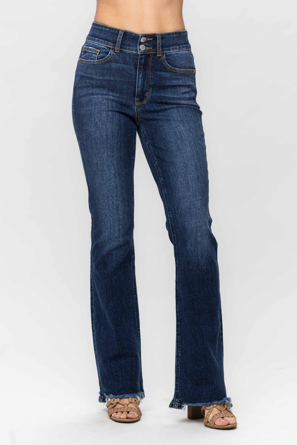 A person wearing trendy and stylish Judy Blue Full Size Frayed Hem Bootcut Jeans with a distressed finish and open-toed sandals is standing against a plain white background.