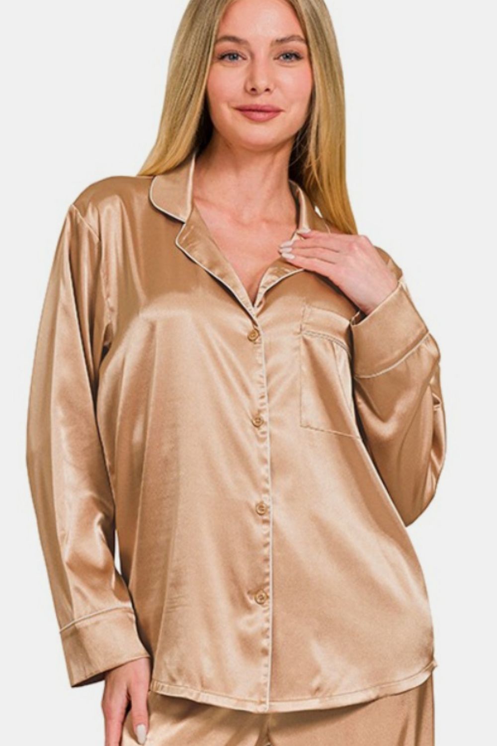 The woman stands elegantly in the Zenana Satin Long Sleeve Shirt and Pants Pajama Set, her hand resting on the collar of the shirt, complementing the ensemble’s elastic waist pants.