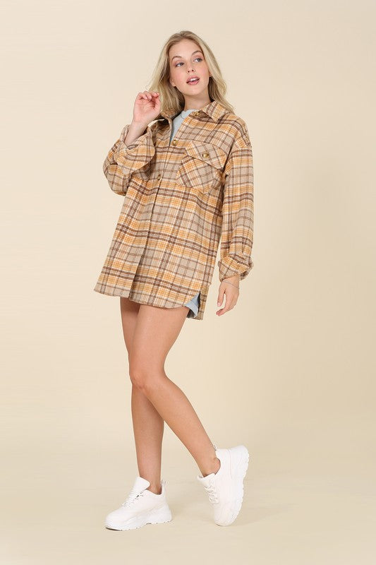 A person wearing the beige and brown Plaid shacket with pockets, featuring long sleeves and large buttons, holds the collar. Blonde hair is visible, adding a touch of elegance to the casual look.