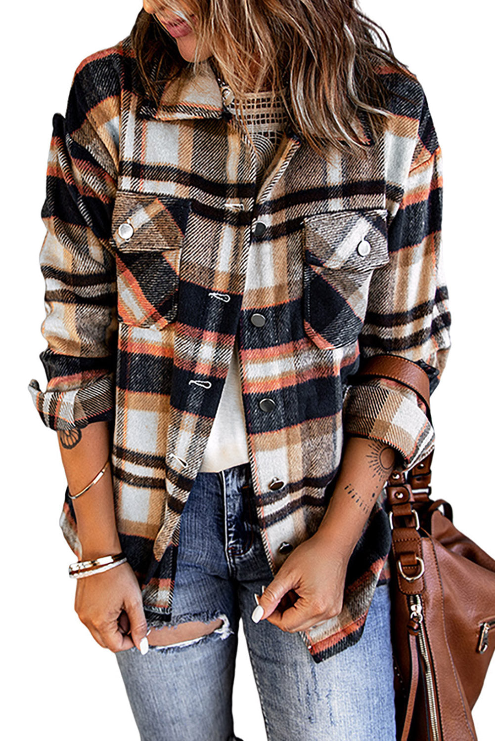 A person wearing a Brown Plaid Button Up Long Sleeve Flannel Shacket layered over a white top with ripped jeans and holding a brown handbag stands against a textured gray wall.