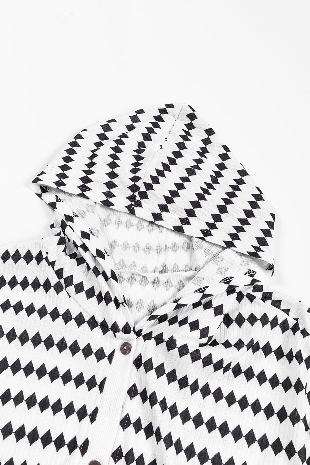 A woman in a Black Stripe Argyle Striped Half Button Oversized Hoodie stands in a room with light green brick walls, a painting of a sailboat, and a fan.