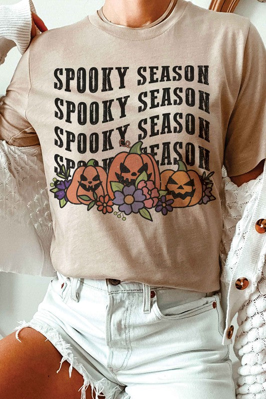 A person is wearing the SPOOKY SEASON PUMPKINS Graphic Tee, featuring "Spooky Season" text and pumpkin graphics, standing with hands by their sides. The unisex sizing ensures a comfortable fit for everyone.