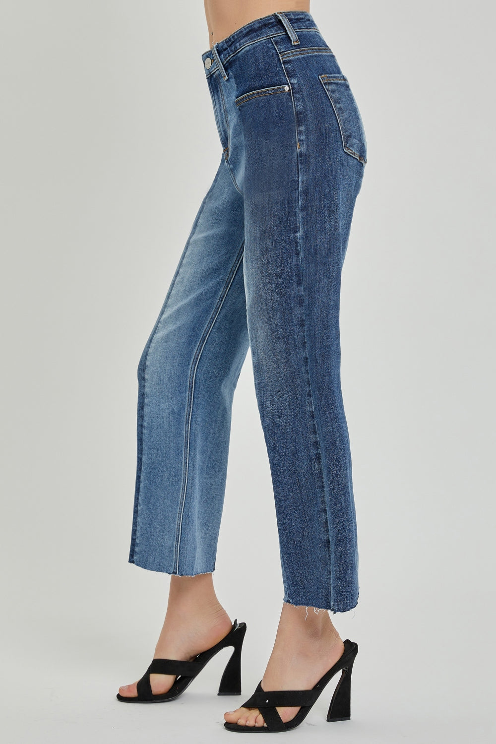 A person wearing RISEN Full Size Mid-Rise Waist Two-Tones Jeans with Pockets, featuring different shades of denim, paired with black open-toe sandals—perfect for everyday wear.