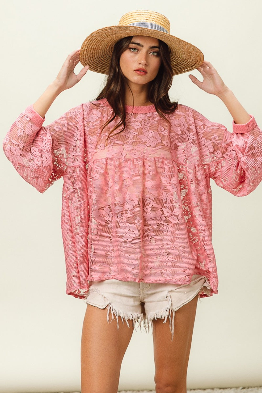 A woman wearing a straw hat, the BiBi Floral Lace Long Sleeve Top, and frayed denim shorts stands against a plain background.