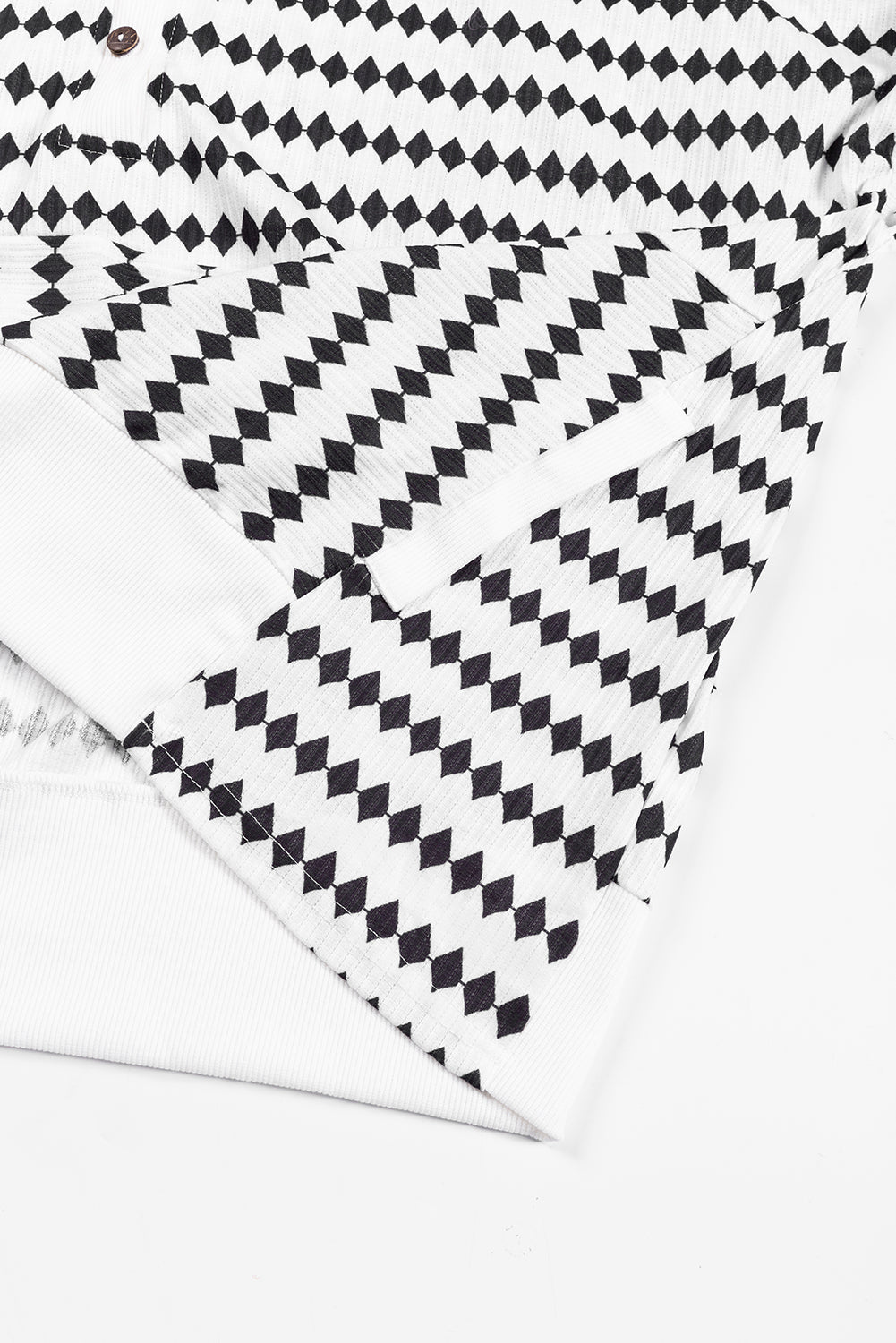 A woman in a Black Stripe Argyle Striped Half Button Oversized Hoodie stands in a room with light green brick walls, a painting of a sailboat, and a fan.