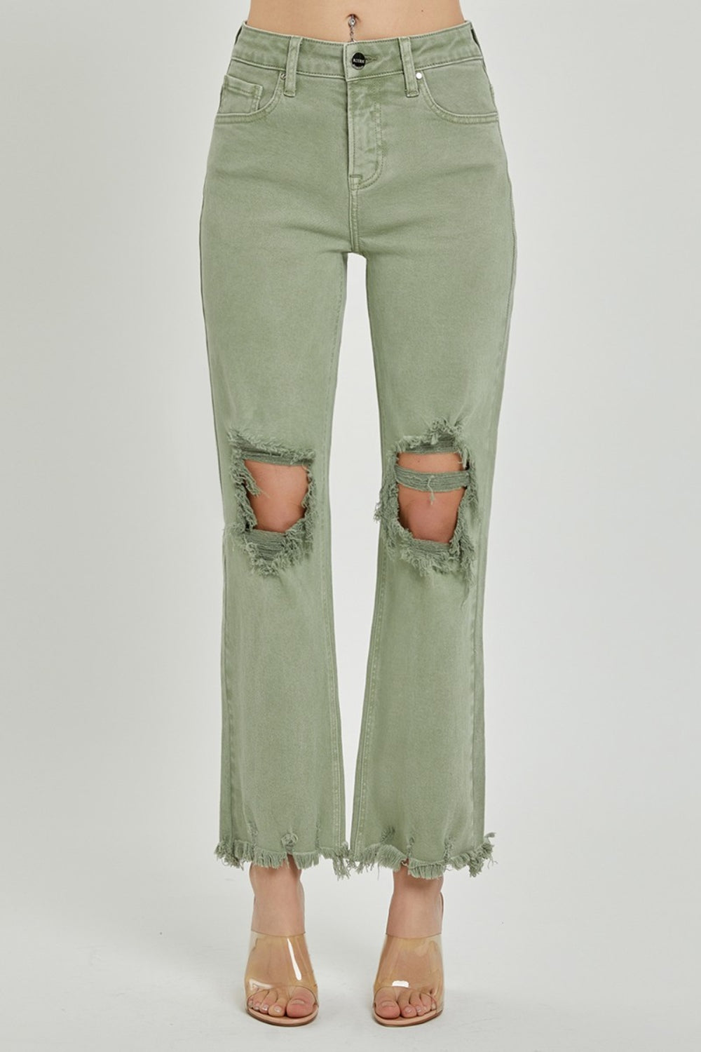 A person wearing RISEN light green distressed ankle bootcut jeans with frayed hems and a beige long-sleeved top, shown from midsection to feet.