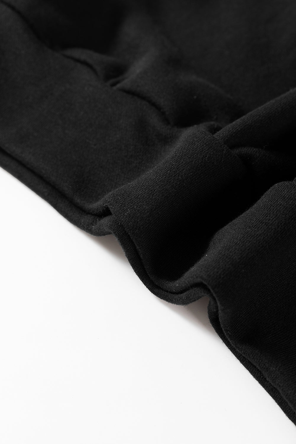 A person wearing a Black Bowknot Dewback Round Neck Sweatshirt, white pants, and a light-colored cap stands against a pink background. The individual has one hand on their hip and is looking down.