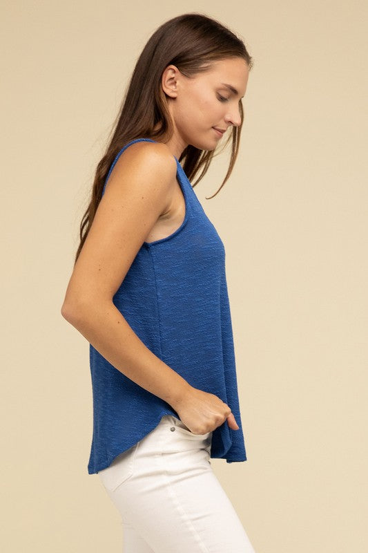 A woman in a stylish and adaptable V Neck Sleeveless Cami Top paired with jeans stands against a beige background. She has long brown hair and maintains a neutral expression.