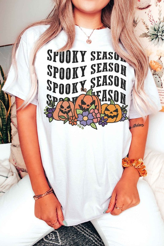 A person is wearing the SPOOKY SEASON PUMPKINS Graphic Tee, featuring "Spooky Season" text and pumpkin graphics, standing with hands by their sides. The unisex sizing ensures a comfortable fit for everyone.