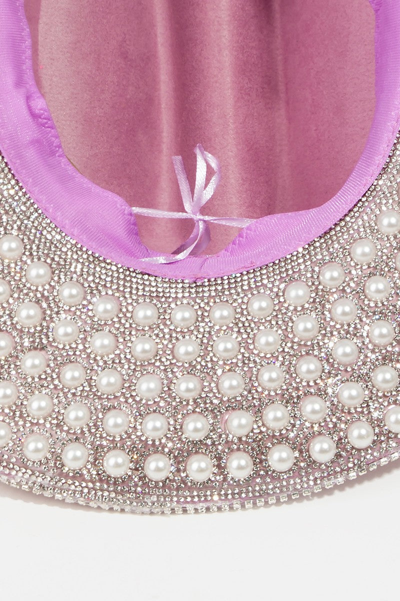 Introducing the Fame Pave Rhinestone Pearl Trim Cowboy Hat: a glamorous Western accessory in light pink, featuring exquisite silver beading along the brim, set against a plain white backdrop.