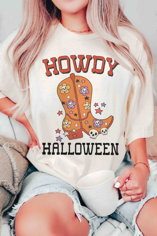 Person wearing the HOWDY HALLOWEEN Graphic Tee, a 100% cotton white t-shirt featuring the words "Howdy Halloween" along with a decorative boot embellished with skulls and flowers.