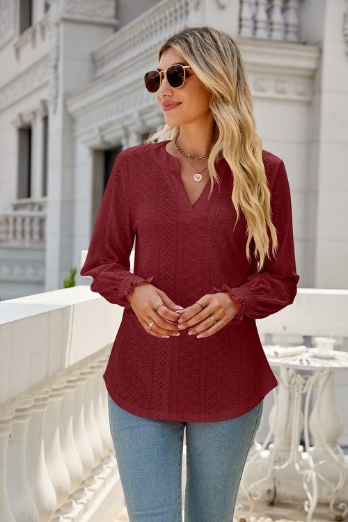 A woman wearing sunglasses, a light pink Women Long Sleeve TOP, and blue jeans stands on a balcony.