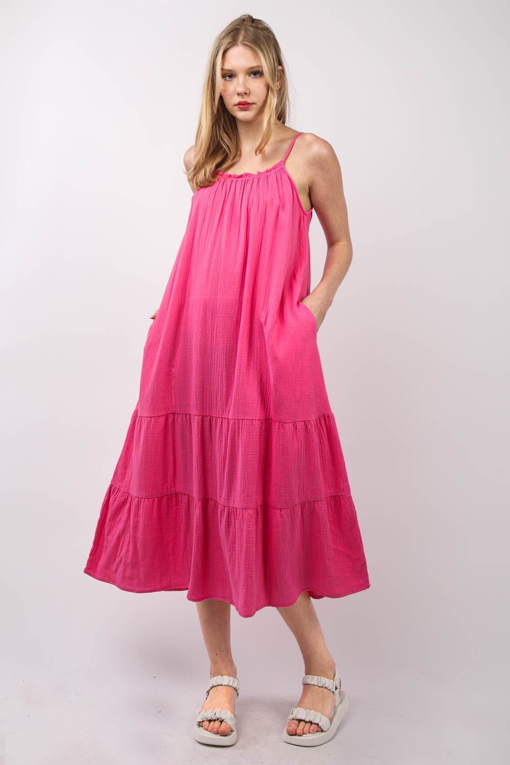 A person with long blonde hair is wearing a bright pink, VERY J Ruffled A-Line Midi Cami Dress and white sandals, standing against a plain background.