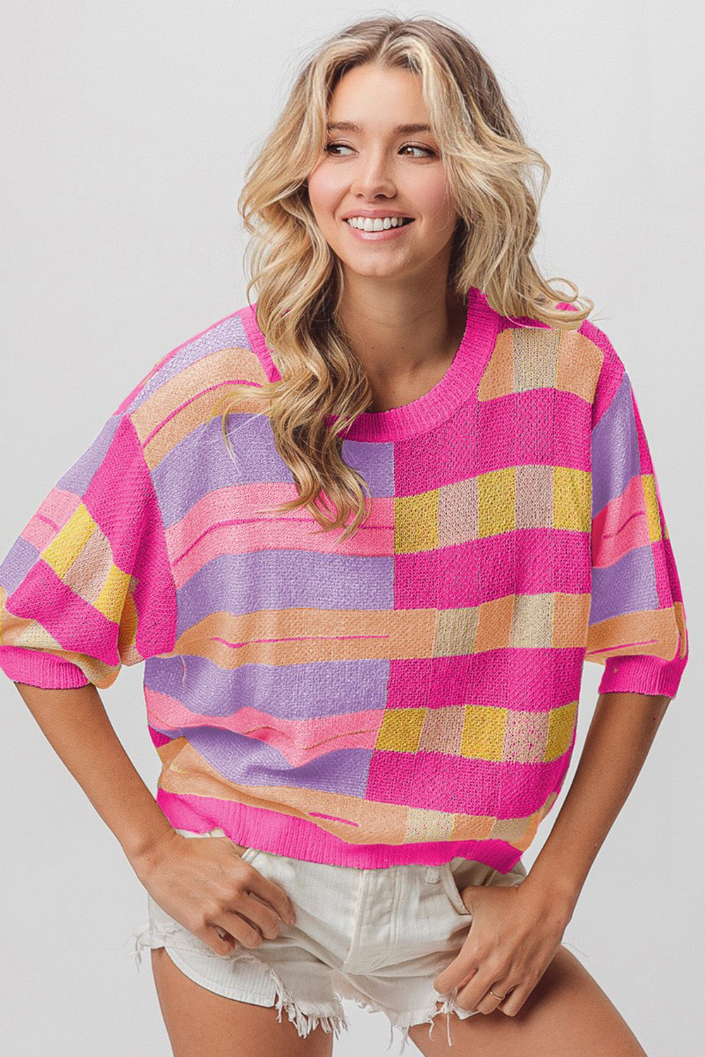 A person with long, wavy hair is wearing a BiBi Multi Color Striped Round Neck Knit Top and white shorts, standing against a plain background.