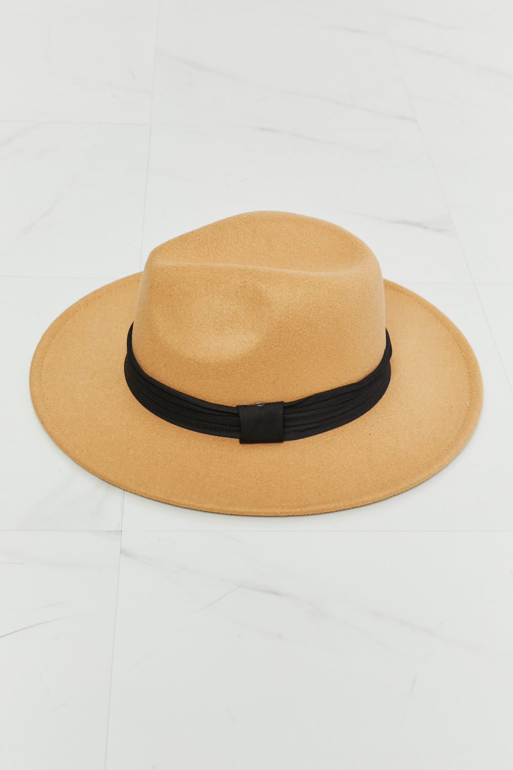 A woman in a white dress with adjustable straps, paired with the dark tan Fame You Got It Fedora Hat featuring a black band, looks over her shoulder and smiles.