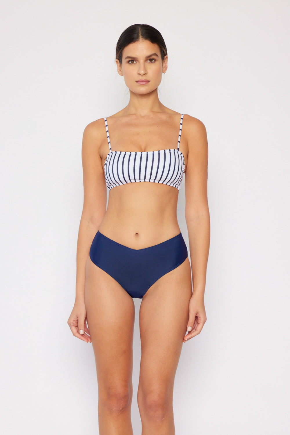 Person showcasing the Marina West Swim Striped Bikini Set, featuring a striped bikini top and solid navy bottoms, standing against a plain background.