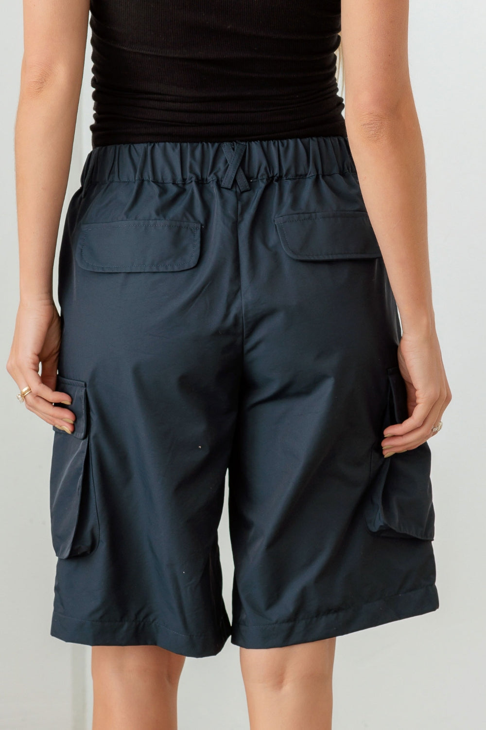 Person wearing a black sleeveless top and Le Lis Navy Cargo Bermuda Shorts with pockets, perfect for a warm-weather wardrobe.