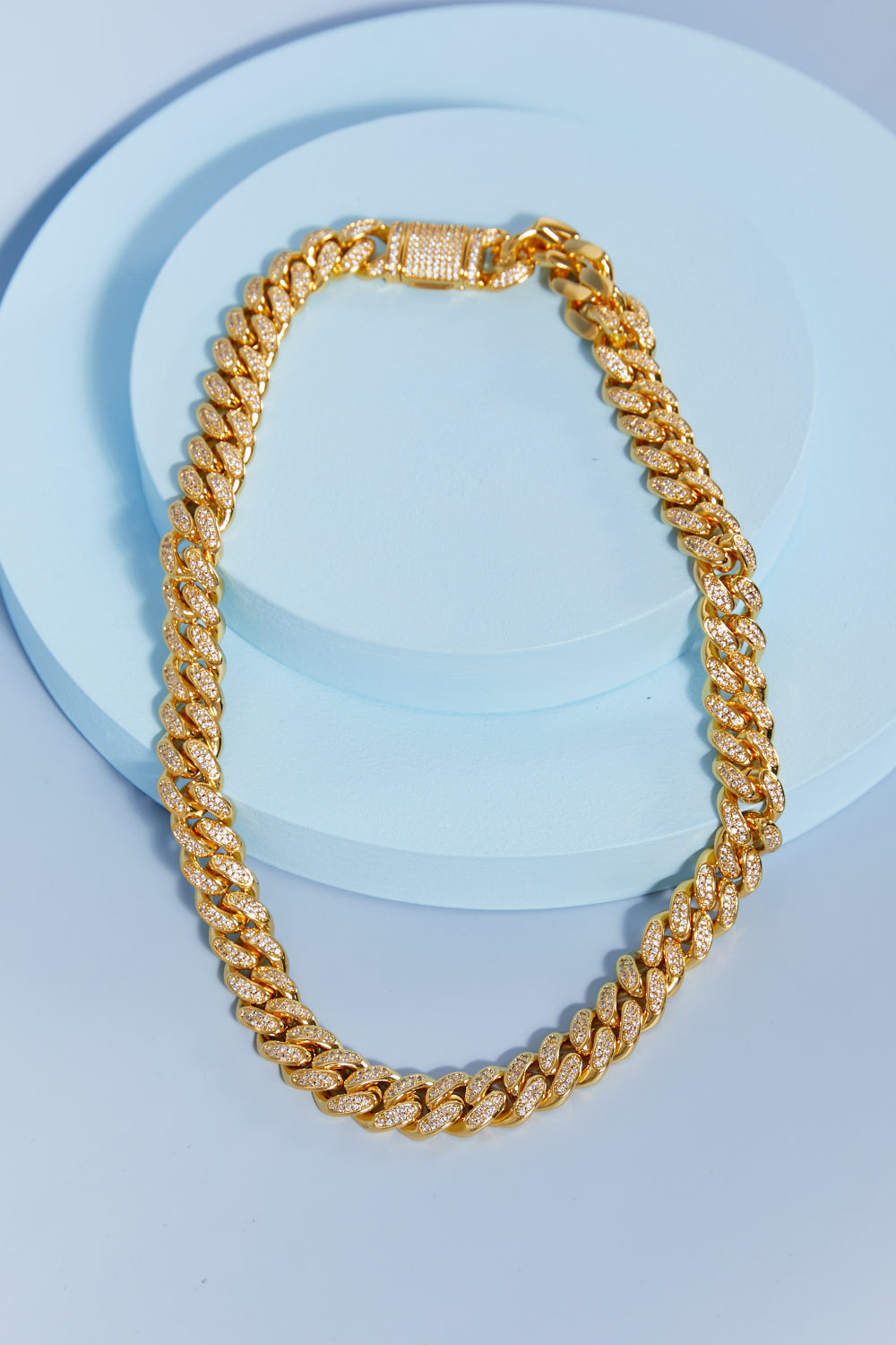 Brass Curb Chain Necklace elegantly displayed on a light blue round surface.